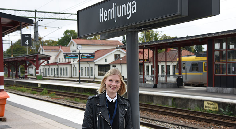 Person som står vid en järnvägsstation där det står Herrljunga på en skylt..