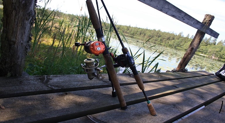 Foto: Birgitta Saunders. Fotot visar två kastspön som står uppställda på en brygga.