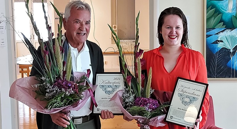 Två personer som har tagit emot ett diplom och blommor
