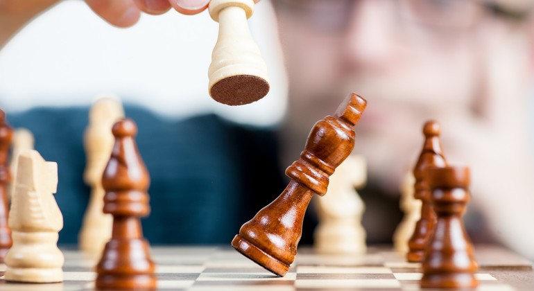 Schack i brun och vit färg och en hand som flyttar en spelare.