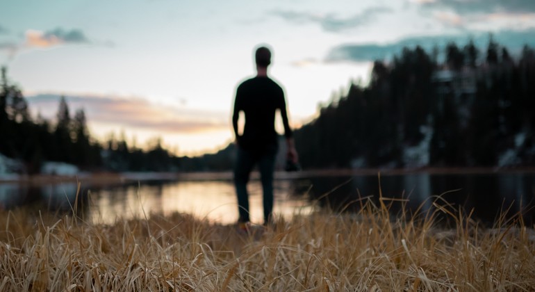 En människosiluett som befinner sig vid en sjö