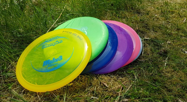 Foto visar frisbees i olika färger, liggande på en gräsmatta