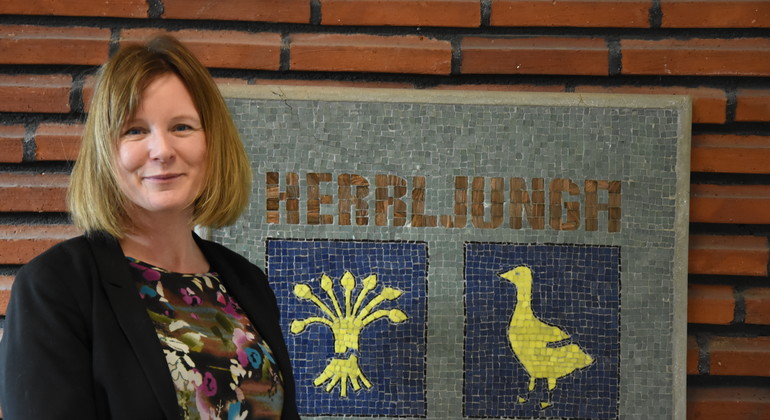 Rektor Linda Rogberg framför Herrljungas kommunvapen.