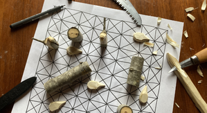 Träpinna, täljkniv och såg på ett brädspel